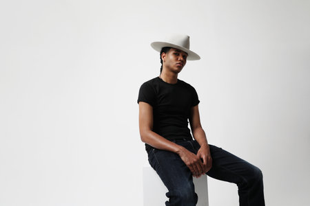 Handsome dark-skinned young man wearing trendy hat and posing indoor. Isolatedの写真素材