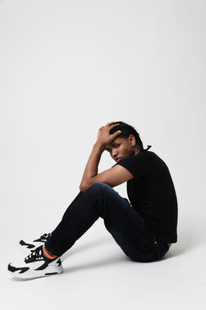 Tired and stressed dark-skinned young man posing in the studio. Vertical.の写真素材