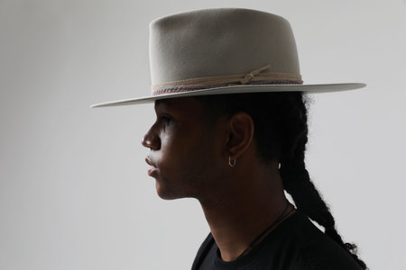 Handsome and carefree dark-skinned young man wearing trendy grey hat. Isolated.の写真素材