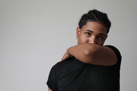 Portrait of handsome dark-skinned young man posing on white wall. Mind set.の写真素材