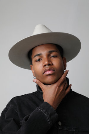 Vertical shot of handsome dark-skinned young man wearing trendy hat. Isolated.の写真素材