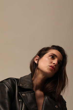 Beautiful young woman posing in studio wearing biker jacket. Vertical mock-up.の写真素材