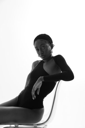 Vertical portrait of young African woman posing on white wall. Black and white.の写真素材