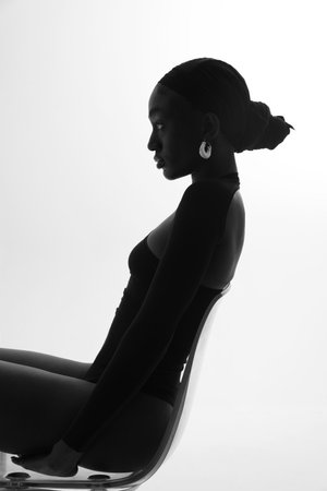 Black and white portrait of young African woman posing on white wall. Vertical.の写真素材