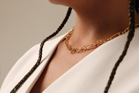 Cropped portrait of woman with a black braids wearing golden chain necklace.の写真素材