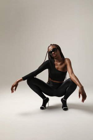 Stylish young African American woman with long braids posing on white wall.の写真素材