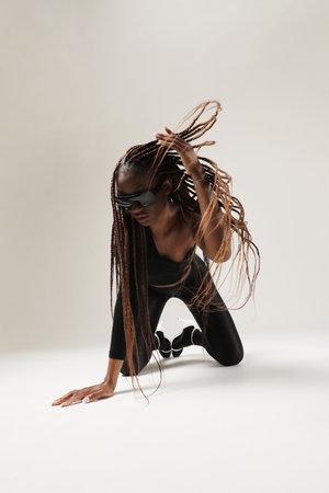 Young African American woman with long braids posing on white wall. Vertical.の写真素材