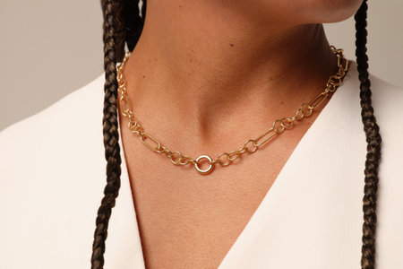Close-up portrait of woman with a healthy skin wearing golden chain necklace.の写真素材