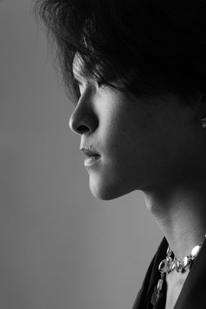 Vertical close-up of confident handsome Asian man posing indoor. Black and white