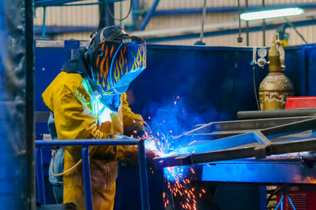 Welder in blue suit, working hard With His torch