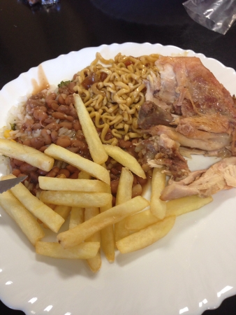 Lunch on a white plate with french fries chicken beans pasta and riceの素材