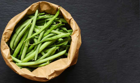Photography of green beans in a brown paper bag on slate background for menu, label or sign / The...