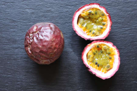 Photography of two passion fruits, one whole, the other cut in half on slate background for food illustrationsの写真素材