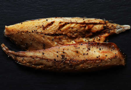 Photography of two fillets of smoked mackerel with ground black pepper on slate background for food illustrationsの写真素材
