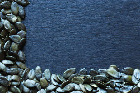 Photography of pumpkin seed s on slate background for menus, labels or signs