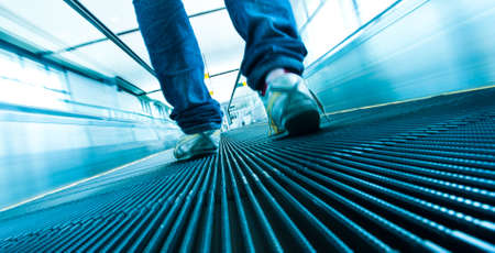 Man step on moving escalator perspective view  ground level の写真素材