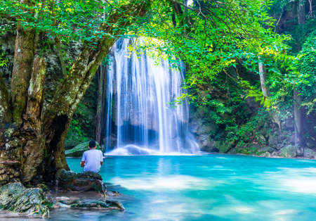 A man look at waterfall while sitting under the treeの写真素材