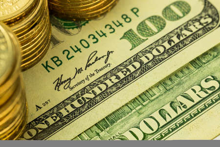 Golden coins on one hundred dollars banknote