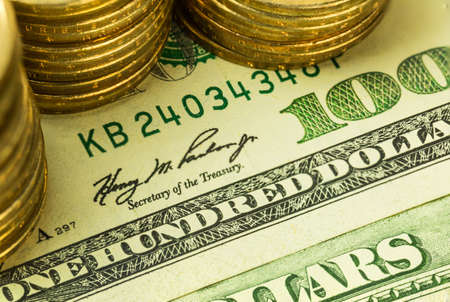 Golden coins on one hundred dollars banknote
