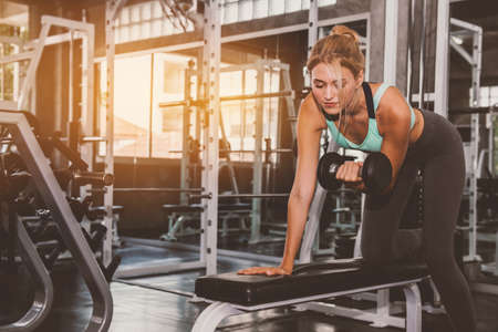 Fitness girl lifting dumbbell in the gym