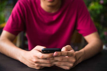 A man look at mobile phone at coffee shop while waiting for orderの写真素材