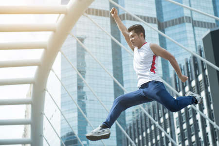 Man in sport clothing jumping while exercising outsideの写真素材