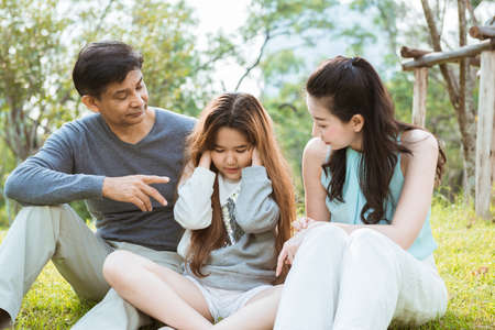 Angry parent scolding and lecturing on the daughter while sitting in the parkの写真素材