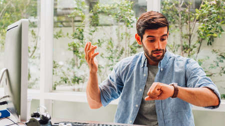 Stressed anxious businessman in a hurry checking time, he is working late and overdueの写真素材