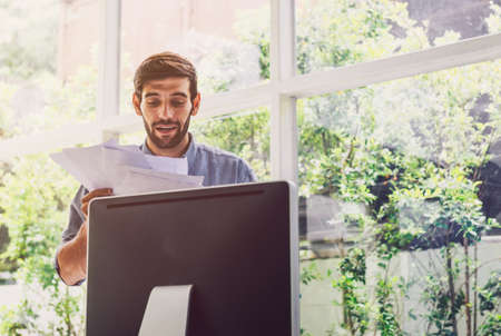 Busy man working on documents front of computer at home office