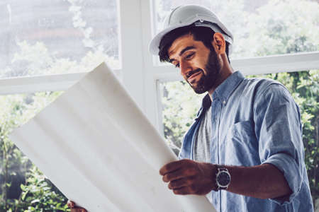 Architect looking at blueprint project with a pleasure and smile in the officeの写真素材