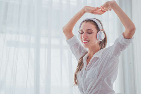 Young woman listening the music with headphones in bedroomの写真素材