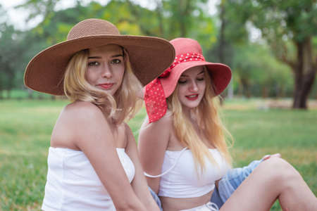 Two young beautiful women talking and chatting in the park