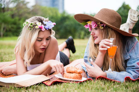 Young beautiful woman read text book and lay on mat and grass field with friend