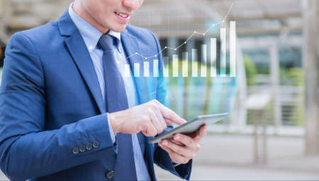 A man using moblie phone for check the growth of revenue graphの写真素材