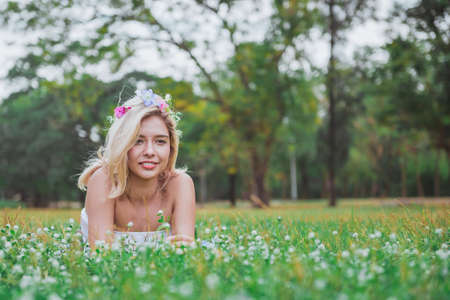 Beautiful girl laying on the grass in spring park and smilingの写真素材