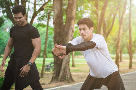 Athletic runner doing stretching exercise, preparing for morning workout in the parkの写真素材