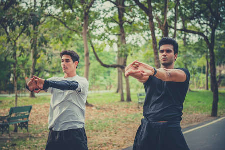 Runner doing stretching exercise, preparing for morning workout in the park