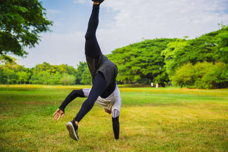 Sportsman doing a handstand on the grass in the park