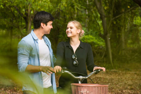 Happy young couple going for a bike ride in the park.の写真素材