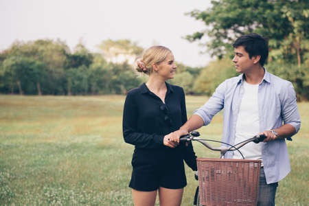 Lovely couple walking through the park with bicycleの写真素材