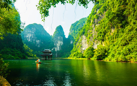 Floating boat rowling around temple on the lake, sorrounded by mountain at Trang Anの写真素材