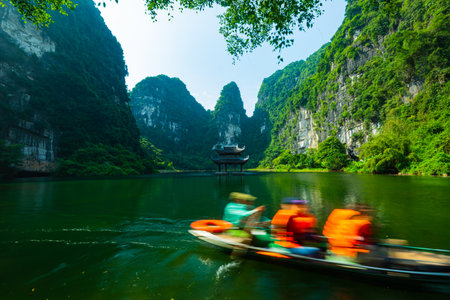 Floating boat rowling around temple on the lake, sorrounded by mountain at Trang Anの写真素材