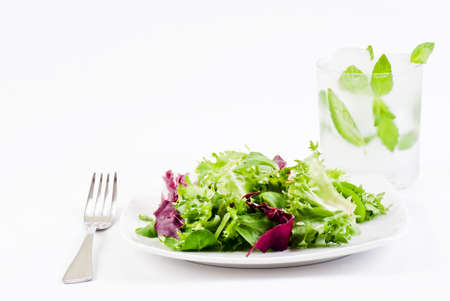 Mix of crisp and sweet lettuce leaves with glas of ice cold water with mintの写真素材