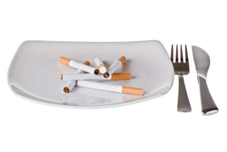 Several cigarettes on the plate with fork and knifeの写真素材