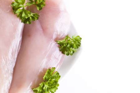 Raw chicken breasts on the plate with parsley - isolatedの写真素材