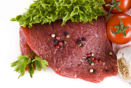 Raw beef frying steak with vegetables isolated over white backgroundの写真素材
