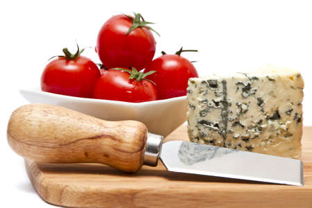 Chopping board with blue cheese and cherry tomatoes over white backgroundの写真素材