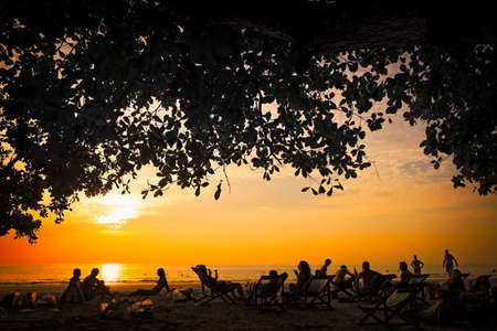 People sitting on the beach in Thailand and enjoying the sunset.のeditorial素材