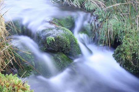 Moss covered stones of a mountain stream, long exposureの写真素材