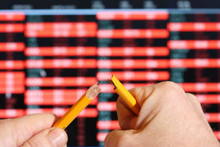 Stockmarket sreen with falling share prices,snapping pencil with stress